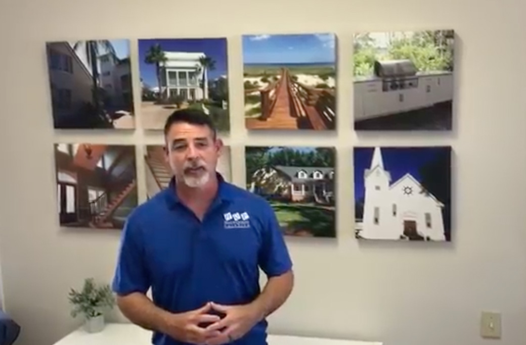 Hall's Quality Painting owner standing in front of photos of completed exterior repainting projects